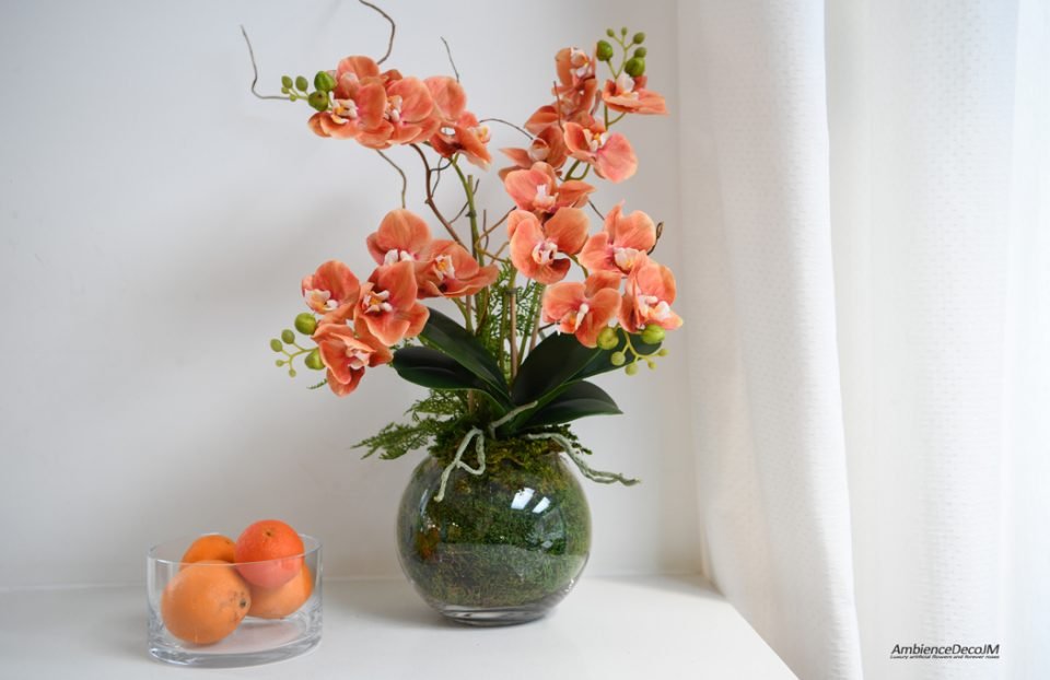 Orange orchids in a globe vase