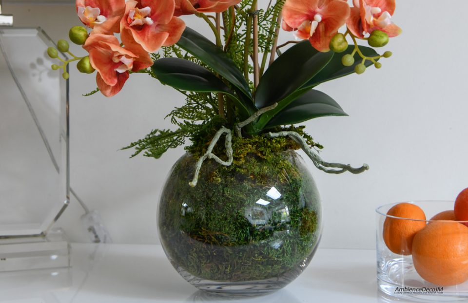 Orange orchids in a globe vase