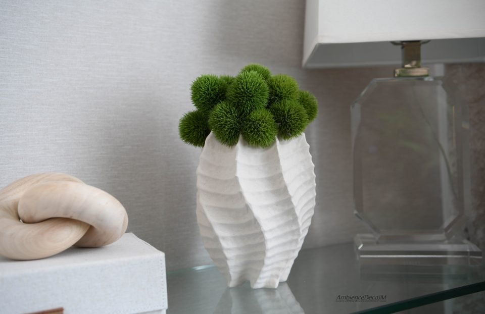 Green artificial dianthus arrangement in a sculptural white vase styled in a modern interior