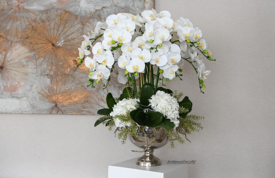 White real-touch Phalaenopsis orchids and hydrangeas with realistic green foliage in a silver pedestal vase.
